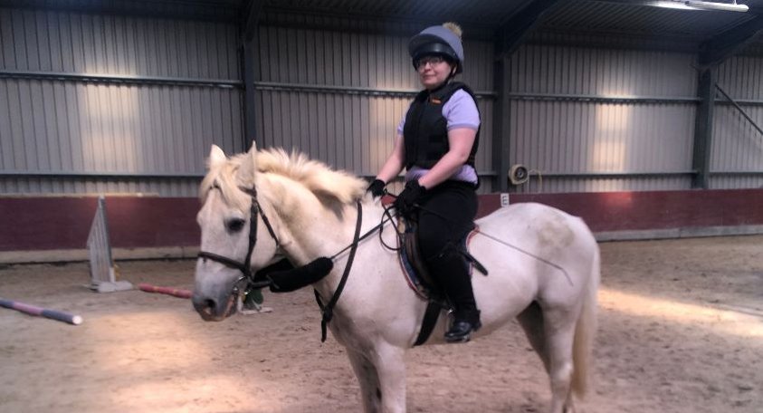 Woman using magnetic stirrups on a grey pony.